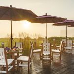 4 poly table and chair sets lined up on a wood deck.