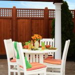 Amish crafted round poly outdoor dining table and 4 chairs on stone patio under pergola