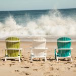 Amish crafted poly adirondack chairs in sand as surf crashes in front of them