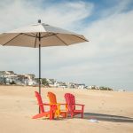 Amish crafted poly outdoor furniture - 3 orange Adirondack chairs on beach
