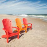 red and orange Adirondack chairs on beach