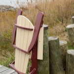 Poly folding Adirondack chair leans against dock post