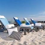 Blue poly chaise lounge chairs lined up on beach