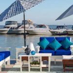 Amish crafted poly outdoor furniture - White deep seating chairs and sofa on dock with boats in background.