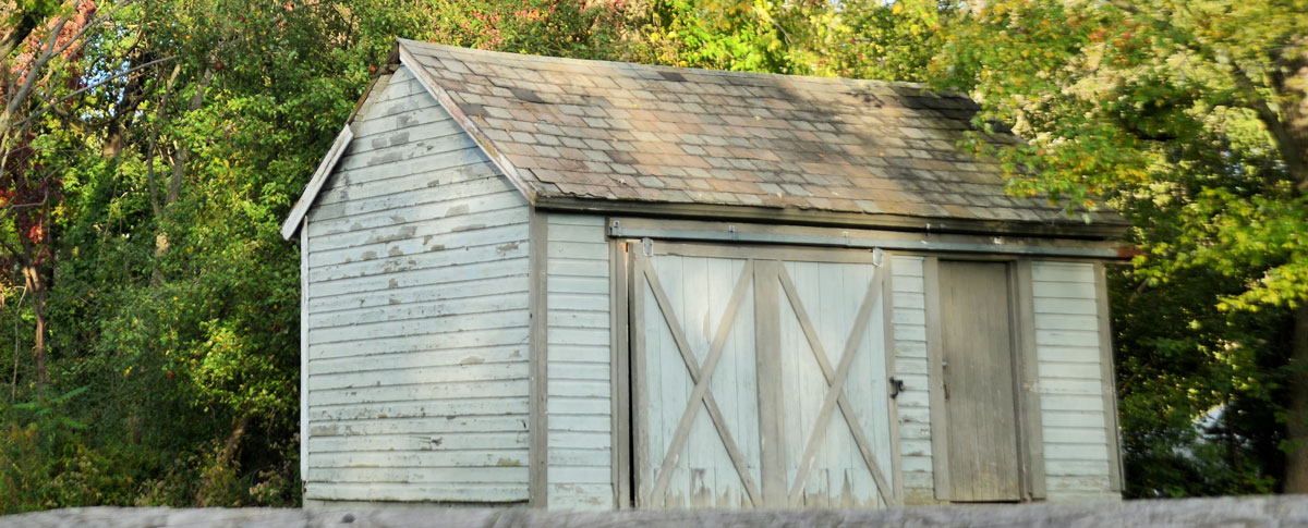 Old barn style shed with white wood siding