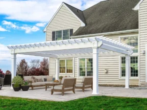 White vinyl veranda pergola attached to the back of a house, with an open lattice roof over a patio seating area.