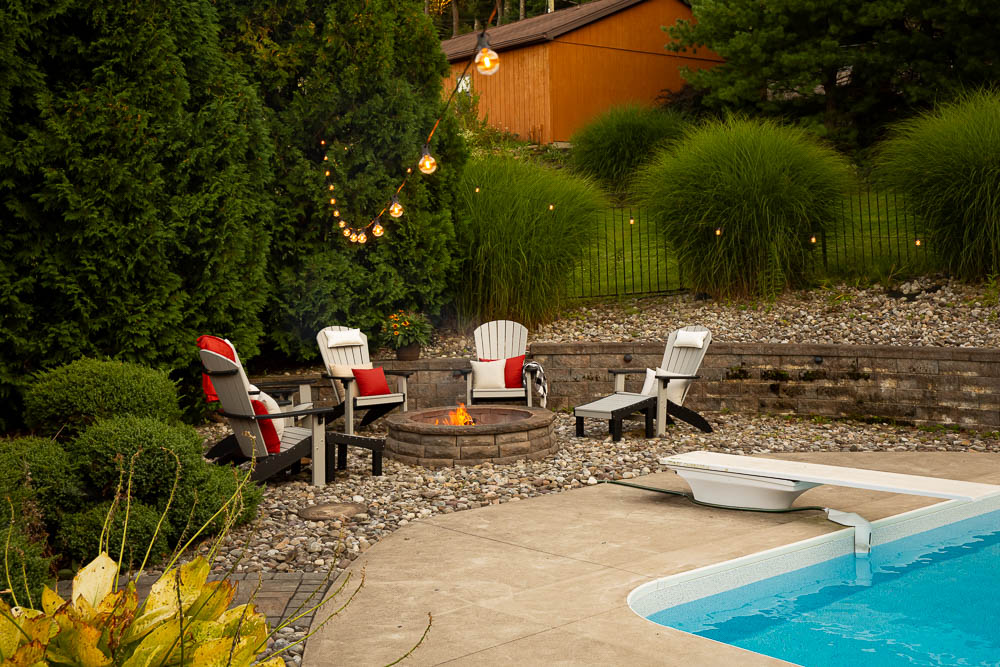 Fire pit and string lights give soft ambience to poolside patio 