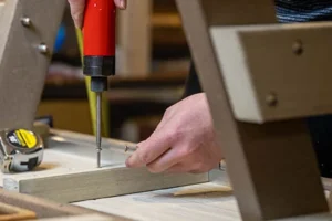 Person screwing marine grade stainless steel screw into poly lumber