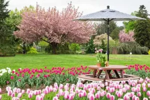 poly picnic table with umbrella in a garden of tulips